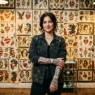 Tattooed woman standing in front of traditional flash art sheets in authentic tattoo studio