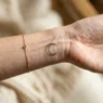 Woman's wrist showing single delicate fine-line moon phase tattoo with soft studio lighting