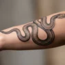 Close-up of elegant snake tattoo wrapping around woman's forearm showing intricate scale detail and smooth shading