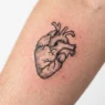 Close-up view of fresh heart tattoo showing detailed linework and skin texture in studio lighting