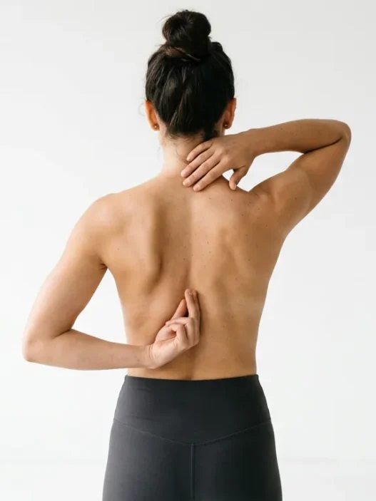 Woman demonstrating spine tattoo placement options with hands positioned along different vertebrae areas