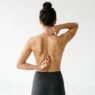 Woman demonstrating spine tattoo placement options with hands positioned along different vertebrae areas