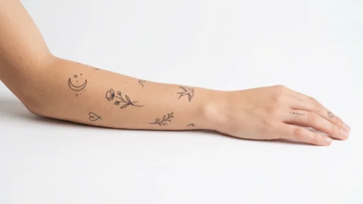 Collection of various tiny minimalist tattoos displayed on clean white background with studio lighting