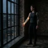 Woman standing by industrial loft window, cybersigilism blackwork tattoo on forearm lit by dramatic side light against exposed brick wall