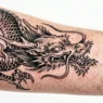 Close-up of fresh dragon tattoo on women's skin showing detailed linework and vibrant colors