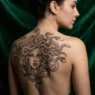 Fine line Medusa portrait tattoo with serpent hair displayed against emerald green velvet in dramatic studio lighting