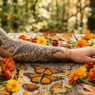 Woman's forearm with Monarch butterfly tattoo surrounded by marigolds and amber leaves in warm garden light