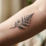 Extreme macro view of delicate botanical sprig tattoo on woman's inner forearm showing fine ink pigment in skin texture
