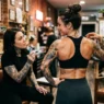 Woman consulting with tattoo artist about spine placement for botanical design in studio setting