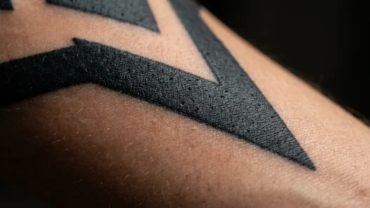 Extreme macro view of bold black and grey tattoo tonal range on a woman's forearm in soft studio lighting