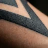 Extreme macro view of bold black and grey tattoo tonal range on a woman's forearm in soft studio lighting