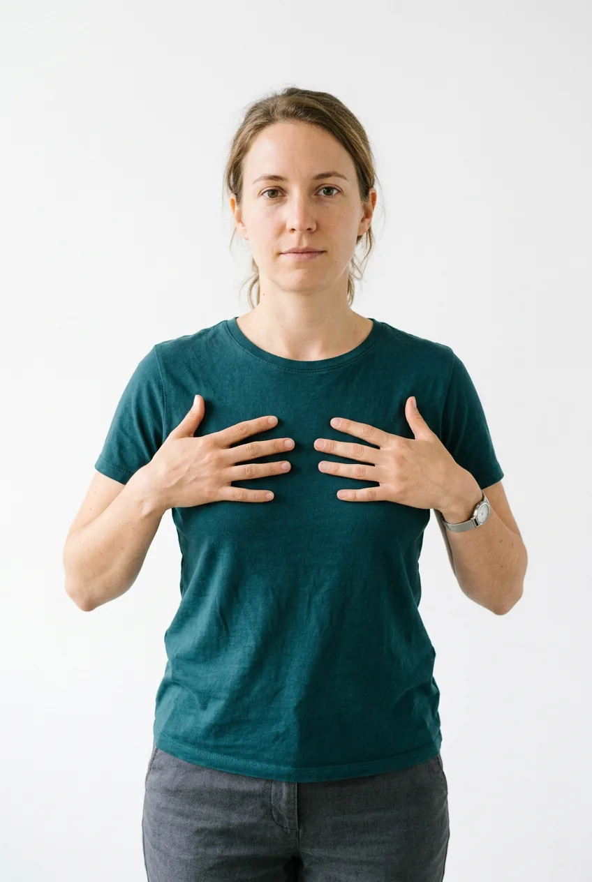 Woman holding both hands flat and symmetrically against her chest to indicate tattoo width and scale