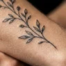 Extreme macro view of delicate fine line botanical stem tattoo on a woman's forearm with ink pigment visible in skin texture