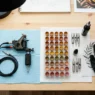 Overhead view of tattoo workstation with warm-toned pigment caps and tattoo machine arranged neatly under studio lights